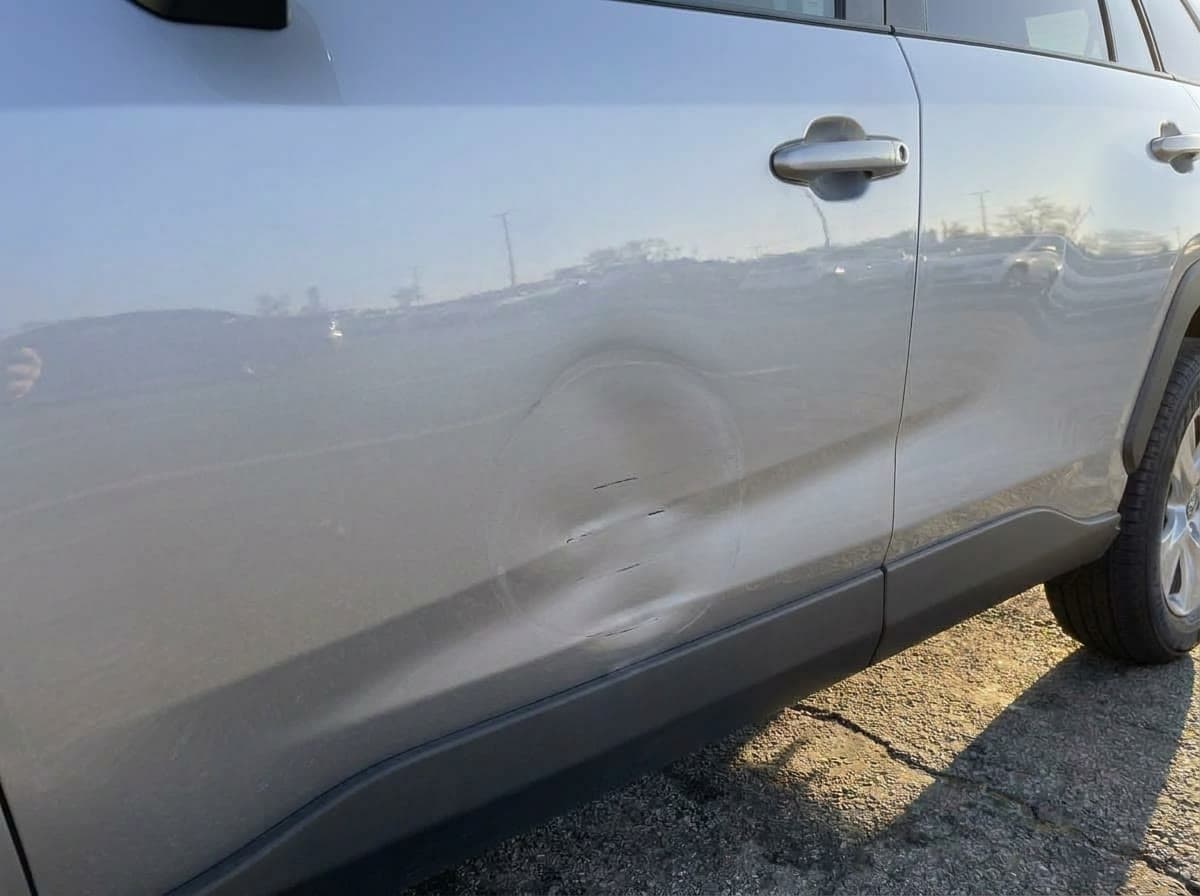 The same door at return, afternoon sun, with a dent and scratches